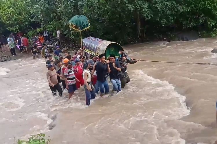 Tangkapan layar video warga menggotong keranda jenazah melewati sungai menuju areal pemakaman.