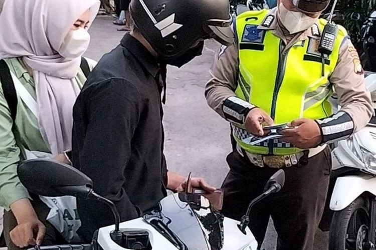 Ilustrasi polisi melakukan tilang manual di Operasi Patuh Jaya 2025.