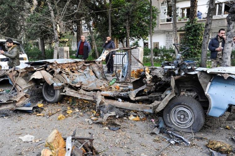 Warga melihat mobil yang rusak berat usai meledak akibat serangan bom di dekat Kedutaan Besar Rusia di Damaskus, Suriah, Kamis (24/1/2019). (AFP/SANA)