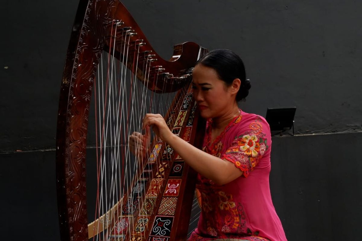 Musisi asal Bandung, Sisca, tengah memainkan harpa toraja. 