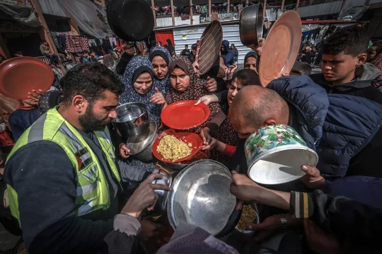 Pengungsi Palestina berkumpul untuk menerima makanan di sekolah negeri di Rafah di Jalur Gaza selatan pada 19 Februari 2024.
