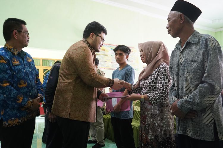 Bupati Hanindhito Himawan Pramana menyerahkan sertifikat program PTSL Tahun 2023 bagi warga di Balai Desa Panjer, Kecamatan Plosoklaten, Senin (20/5/2024).
