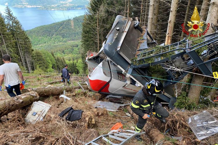 Tim penyelamat menyisir bangkai kereta gantung yang jatuh di dekat puncak jalur Stresa-Mottarone di region Piedmont, Italia utara, pada Minggu (23/5/2021). Sediktnya 13 orang tewas dan 2 anak luka-luka akibat insiden ini.