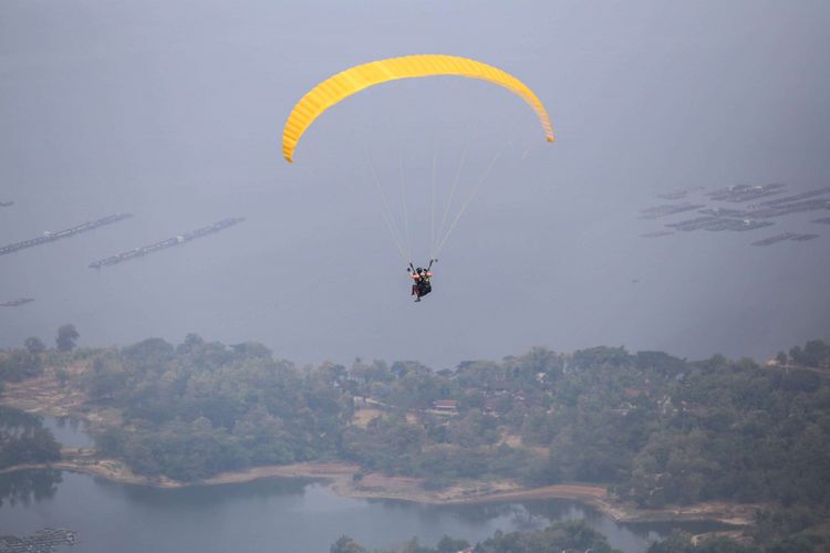 Anggota komunitas Paralayang Soloraya terbang di atas Waduk Gajah Mungkur, Jawa Tengah, Minggu (10/6/2018). Penerbang paralayang  yang lepas landas dari puncak bukit ini bisa menikmati keindahan Waduk Gajah Mungkur dan harus merogoh kocek sebesar Rp 400.000 per orang