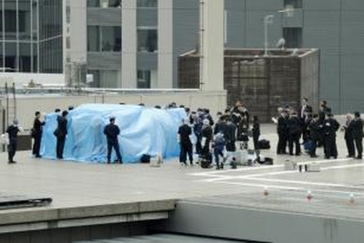 Aparat keamanan Jepang menutupi sebuah drone yang ditemukan di atas atap kantor perdana menteri Jepang di Tokyo, Rabu (22/4/2015). 