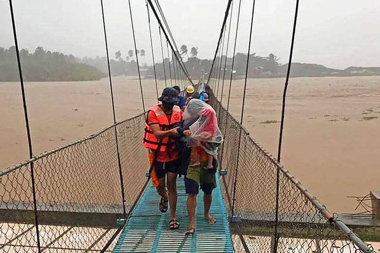 Tim penyelamat membantu warga menyeberangi jembatan saat mereka dievakuasi ke tempat yang lebih tinggi di Kota Tubay, Agusan del Norte, Filipina selatan pada Kamis (16/12/2021). Puluhan ribu orang sedang dievakuasi ke tempat yang aman di Filipina selatan dan tengah ketika Topan Rai menerjang Filipina.