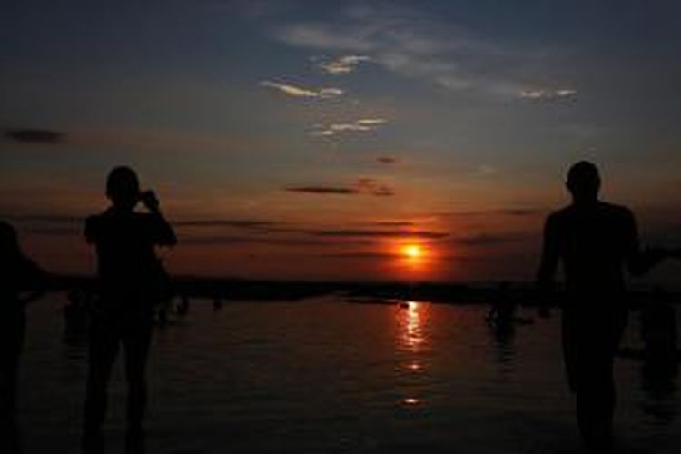 Wisatawan mancanegara menikmati matahari terbenam di Pantai Uluwatu, Badung, Bali, Jumat (2/5/2014). Lokasi Pantai Uluwatu yang agak tersembunyi di antara tebing-tebing batu karang tinggi tersebut ramai dikunjungi wisatawan karena pesona pantainya yang indah dan memukau.   

