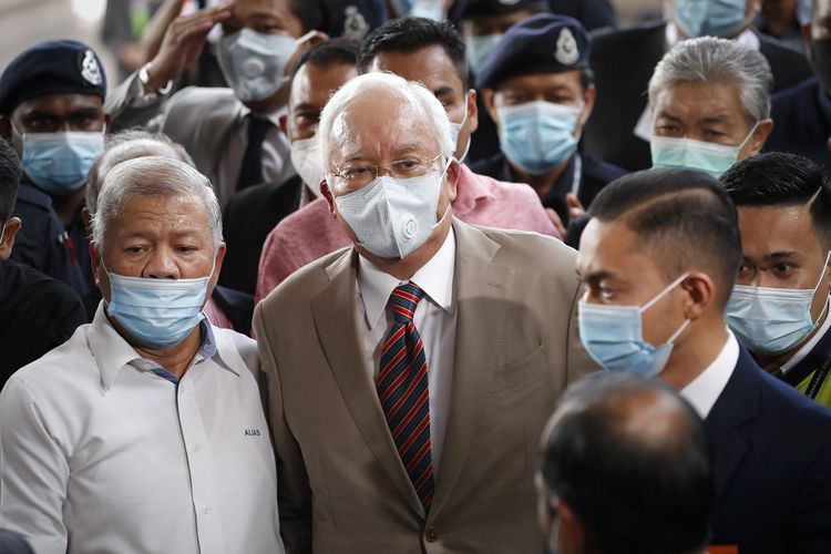 Mantan Perdana Menteri Malaysia Najib Razak (tengah), mengenakan masker berjalan bersama pendukungnya menuju ke ruang persidangan, gedung Pengadilan Tinggi Kuala Lumpur, pada 28 Juli 2020. Najib hadir dalam sidang perdana dari serangkaian dakwaan yang menjeratnya mengenai skandal 1MDB.