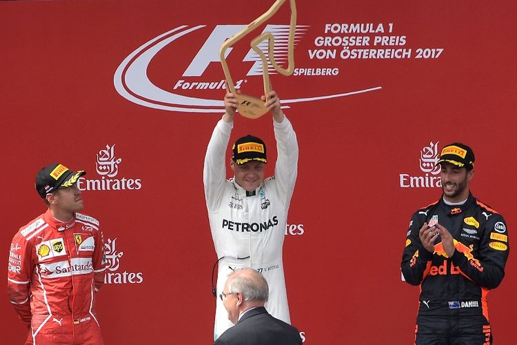 Pebalap Mercedes, Valtteri Bottas (tengah), mengangkat trofi kemenangannya pada balapan GP Austria di Red Bull Ring, Spielberg, Austria, Minggu (9/7/2017).
