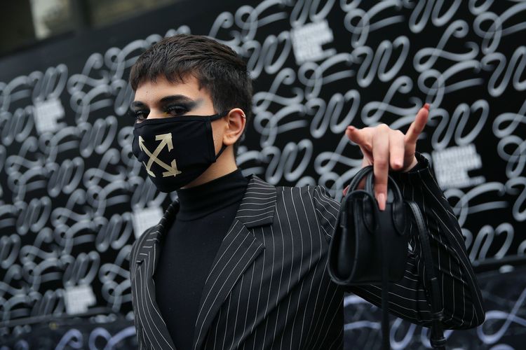 Seorang pengunjung London Fashion Week mengenakan masker.