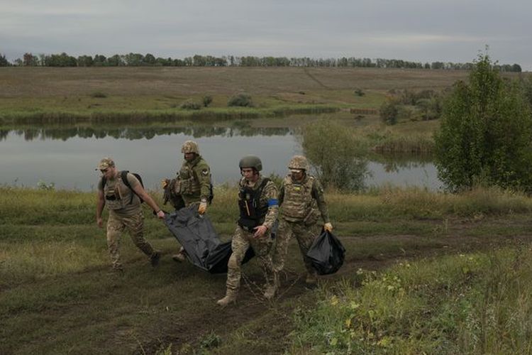 Pasukan Ukraina tersebut mendokumentasikan tempat kejadian dan mengangkat jenazah ke dalam kantong mayat di Kozacha lopan, dekat perbatasan Rusia pada Sabtu (17/9/2022).