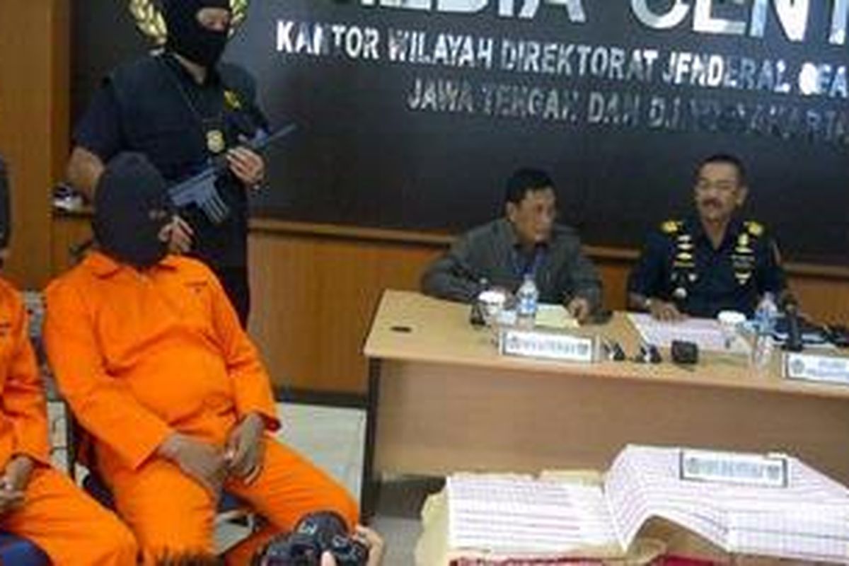 Dua tersangka dan barang bukti berupa dua dus pita cukai palsu yang berhasil diamankan, Selasa (3/4/2012).