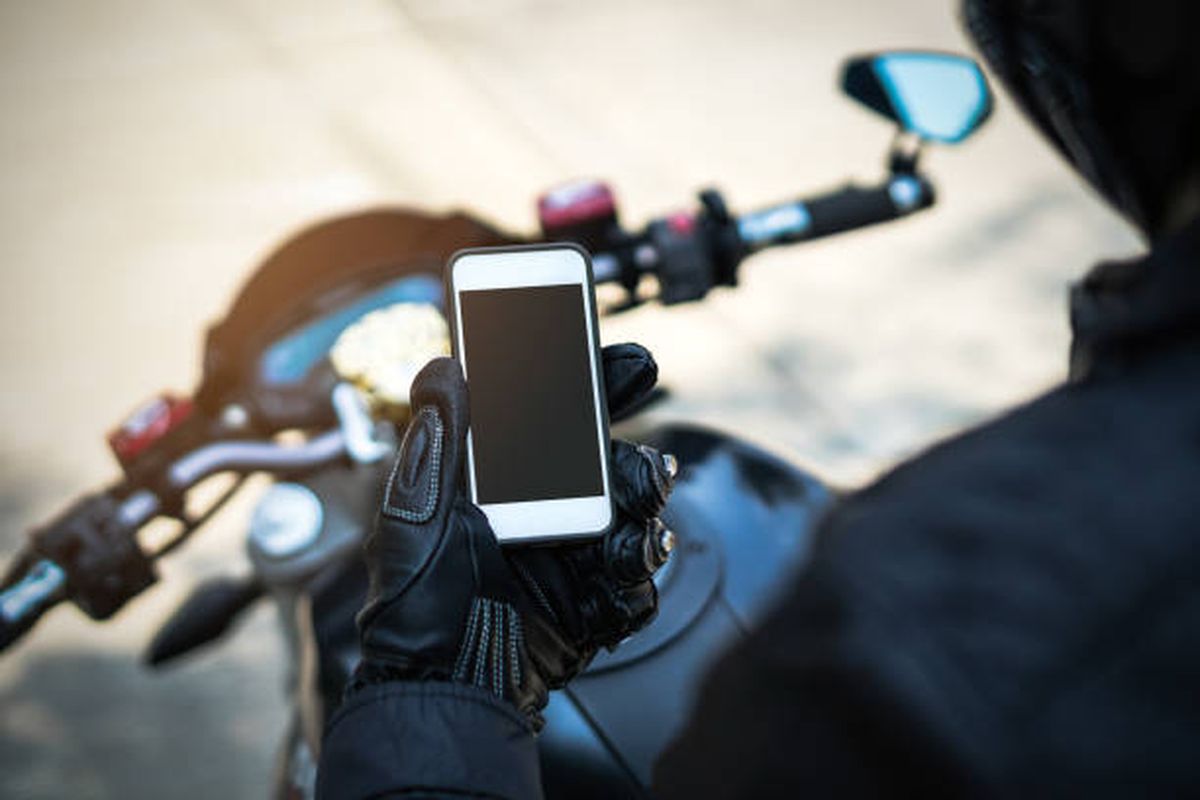 Ilustrasi pengendara sepeda motor menggunakan smartphone.