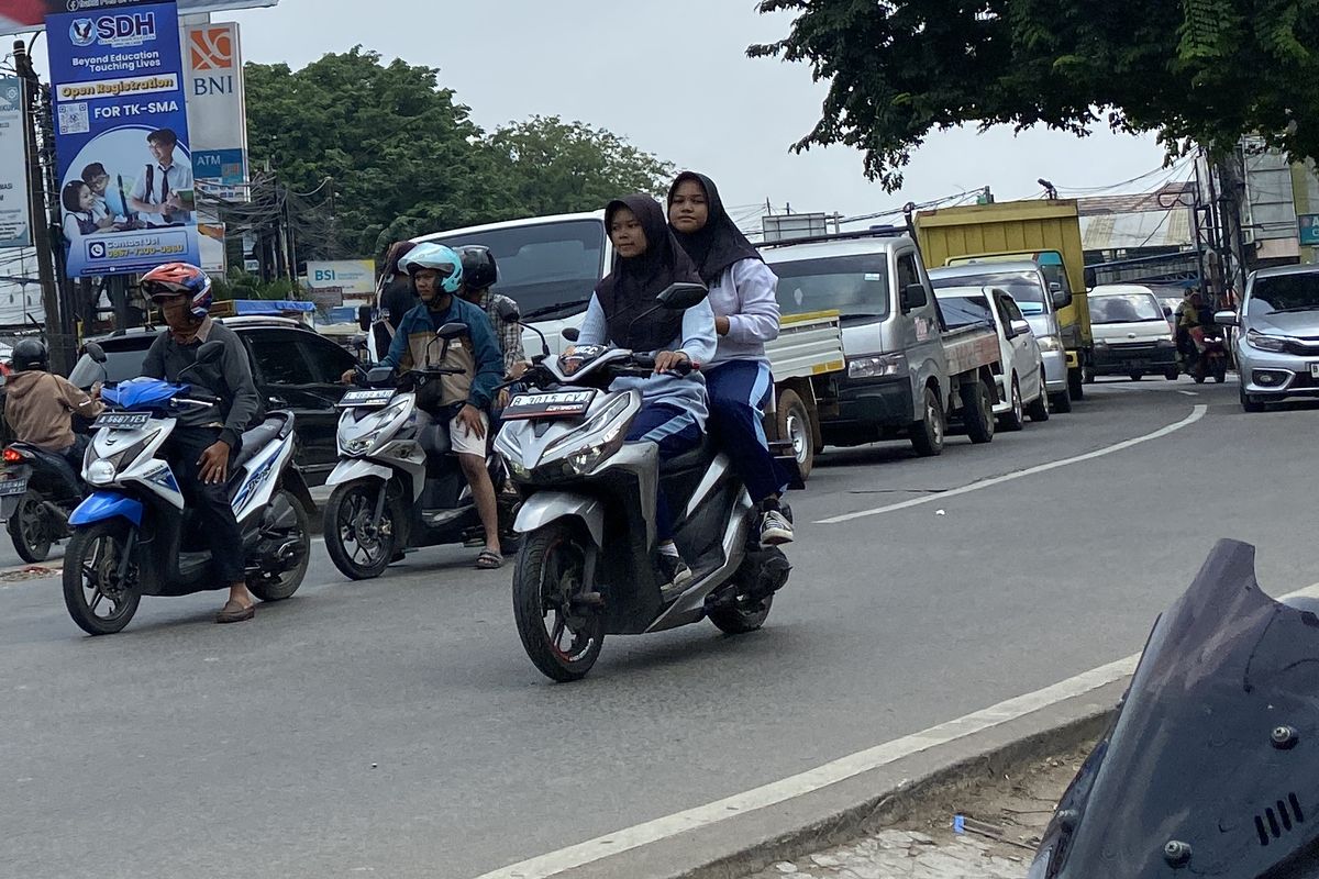 Pelajar SMP berboncengan mengendarai motor tanpa menggunakan helm di jalan raya