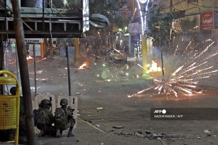 Warga Palestina bentrok dengan pasukan keamanan Israel di pusat kota kota Hebron, Tepi Barat, pada Rabu malam (12/5/2021). 