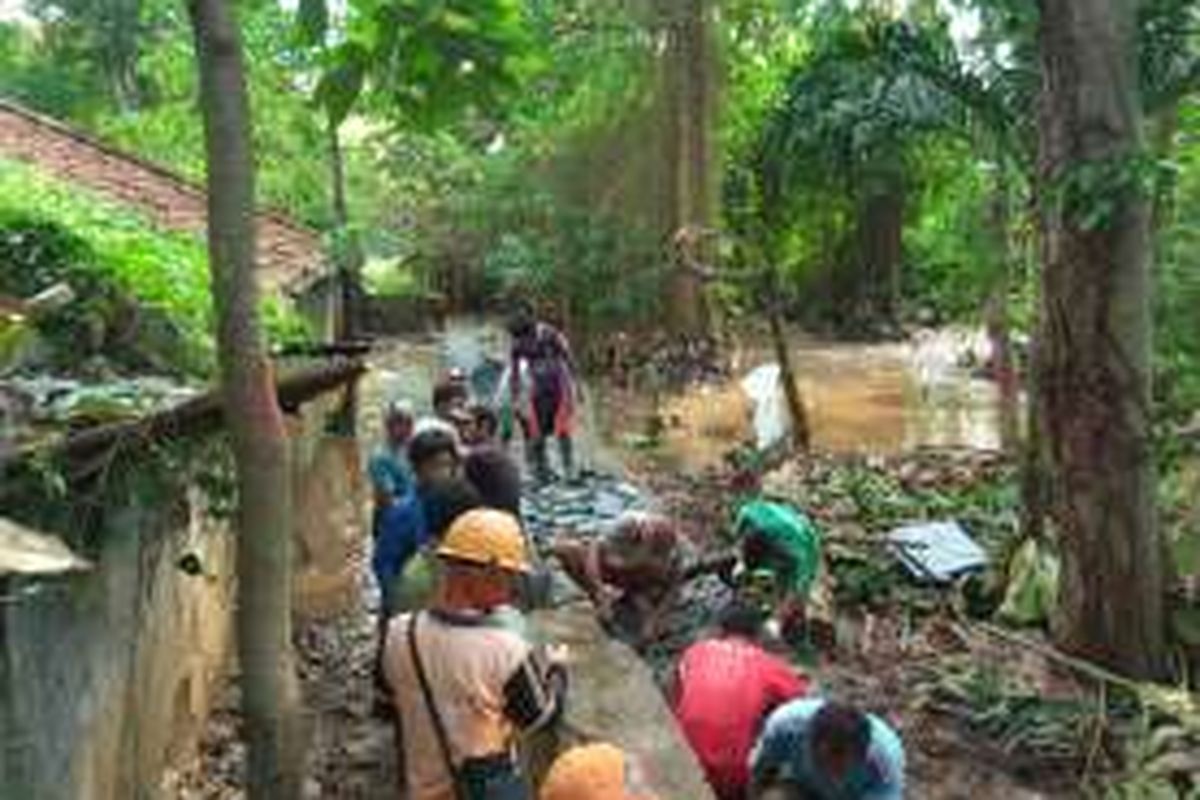 Personel gabungan dari Satgas Tata Air DKI Jakarta, Balai Besar Wilayah Sungai Ciliwung Cisadane, dan PPSU Kelurahan Ulujami, bahu membahu membuat tanggul penahan baru di Komplek Perdatam, Ulujami, Jakarta Selatan, Senin (25/7/2016).