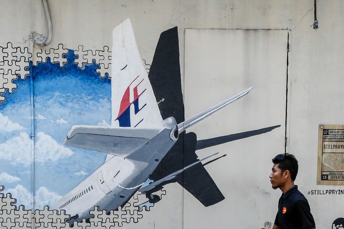 Seorang pelayan berjalan melewati mural penerbangan MH370 di Shah Alam di luar Kuala Lumpur, Malaysia.