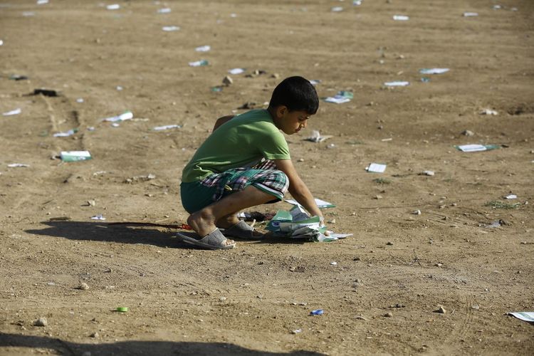 Kondisi perang Israel-Hamas terkini. Seorang anak laki-laki Palestina mengumpulkan selebaran yang dijatuhkan militer Israel, di sebelah timur Kota Gaza, 14 Mei 2018,