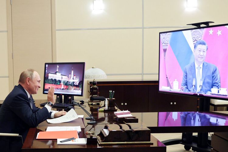 Presiden Rusia Vladimir Putin memberi isyarat selama konferensi videonya dengan Presiden China Xi Jinping, tepat di layar, di Moskow, Rusia, Rabu, 15 Desember 2021.