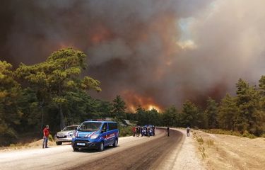 Petugas dan orang-orang menyaksikan kebakaran hutan yang dipicu oleh angin kencang mengamuk di dekat kota Manavgat, Antalya, Turki, pada Rabu (28/7/2021). Pihak berwenang mengevakuasi para warga di Manavgat saat kebakaran hutan mengamuk Rabu melalui hutan. Pasukan Gendarmerie membantu mengevakuasi penduduk dari empat lingkungan di kota keluar dari jalur kebakaran ketika petugas pemadam kebakaran bekerja untuk mengendalikan api.