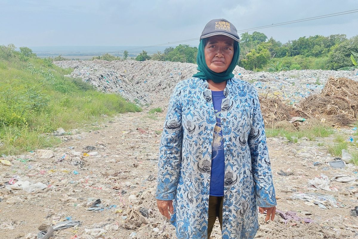 Ibu Sa'duni dengan latar belakang tumpukan sampat di TPA Sumenep.