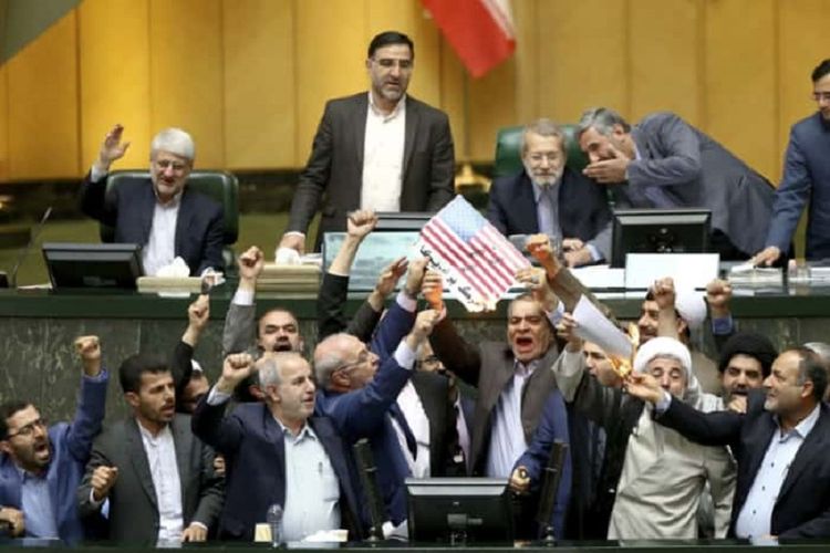 Anggota Parlemen Irak menunjukkan bendera Amerika Serikat yang dibakar ketika sidang Rabu (9/5/2018). Pembakaran itu merupakan reaksi Presiden AS Donald Trump yang memutuskan keluar dari perjanjian nuklir Iran.