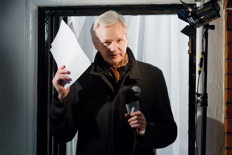 Dalam foto yang diambil pada Desember 2012 ini, Julian Assange menyapa para jurnalis dari jendela kamarnya di kantor kedutaan besar Ekuador di London.