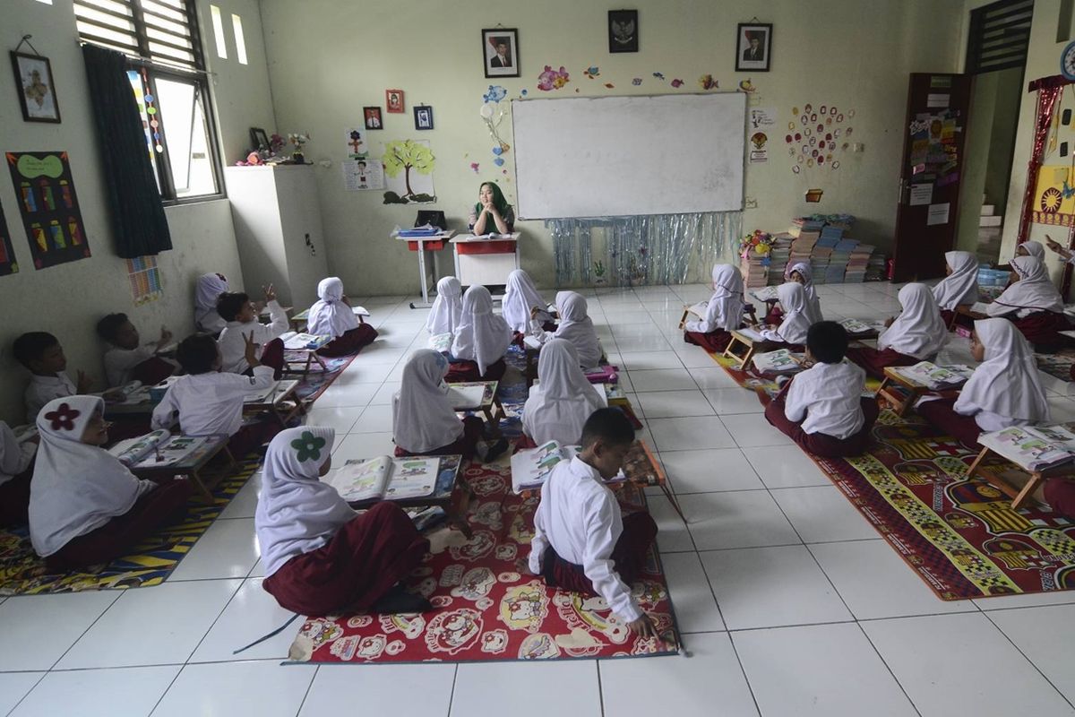 Murid kelas 2 SDN Pekayon Jaya 3 belajar dengan cara lesehan di kelas lantaran sekolahnya tak punya meja-kursi.