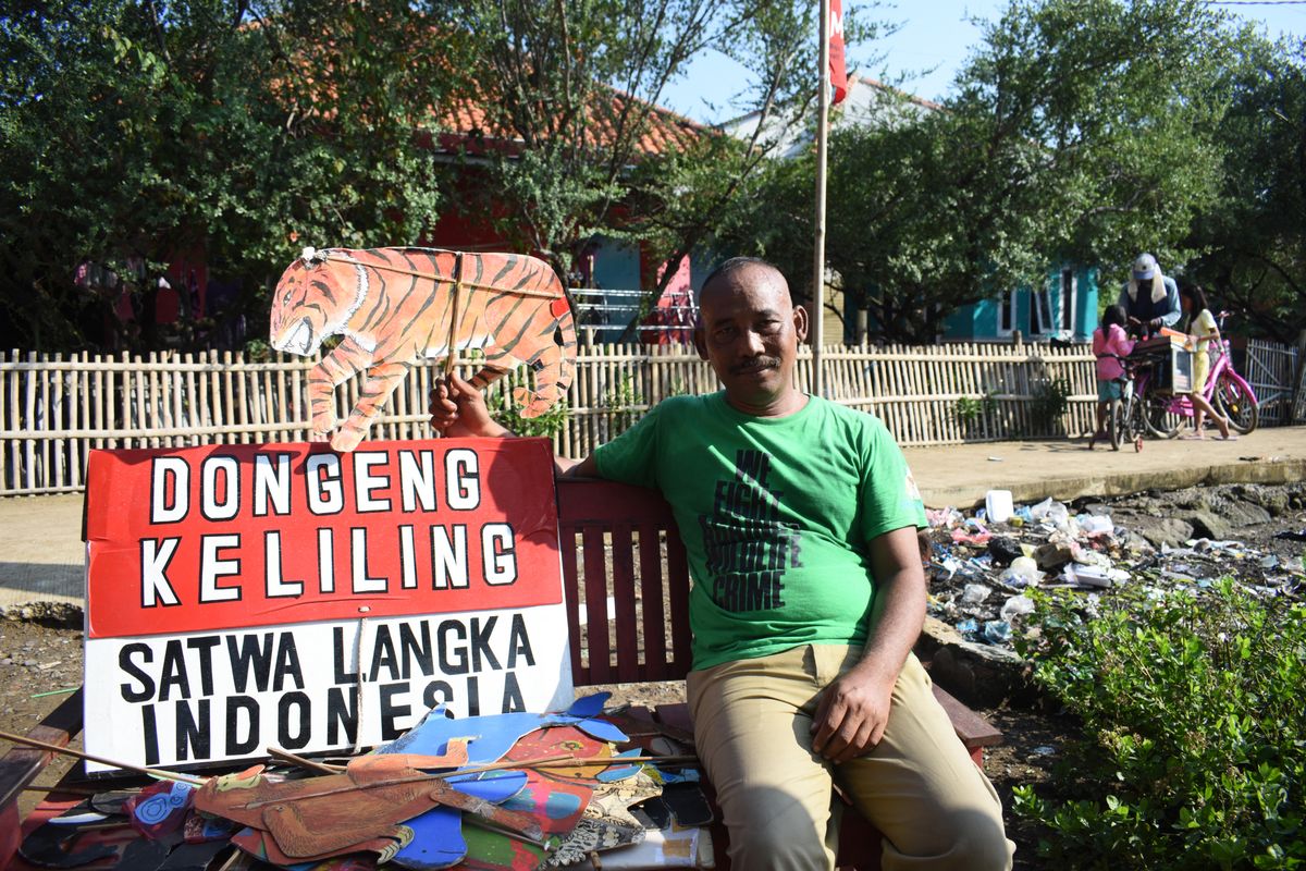 This picture taken on June 19, 2022 shows former teacher Samsudin posing with a cardboard puppet while teaching children about animal conservation at Cemara Kulon village, in Indramayu. Samsudin is educating the young about the plight of the critically endangered Javan rhino - the world's rarest - with puppets on a stick, comical expressions and exaggerated voices, spreading his message of conservation one story at a time. TIMUR MATAHARI / AFP