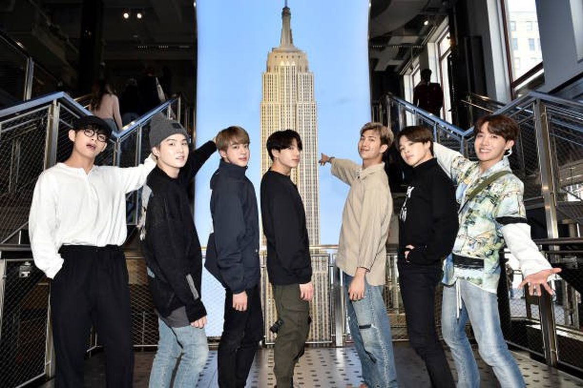 Boyband BTS berpose dengan latar belakang miniatur Gedung Empire State.