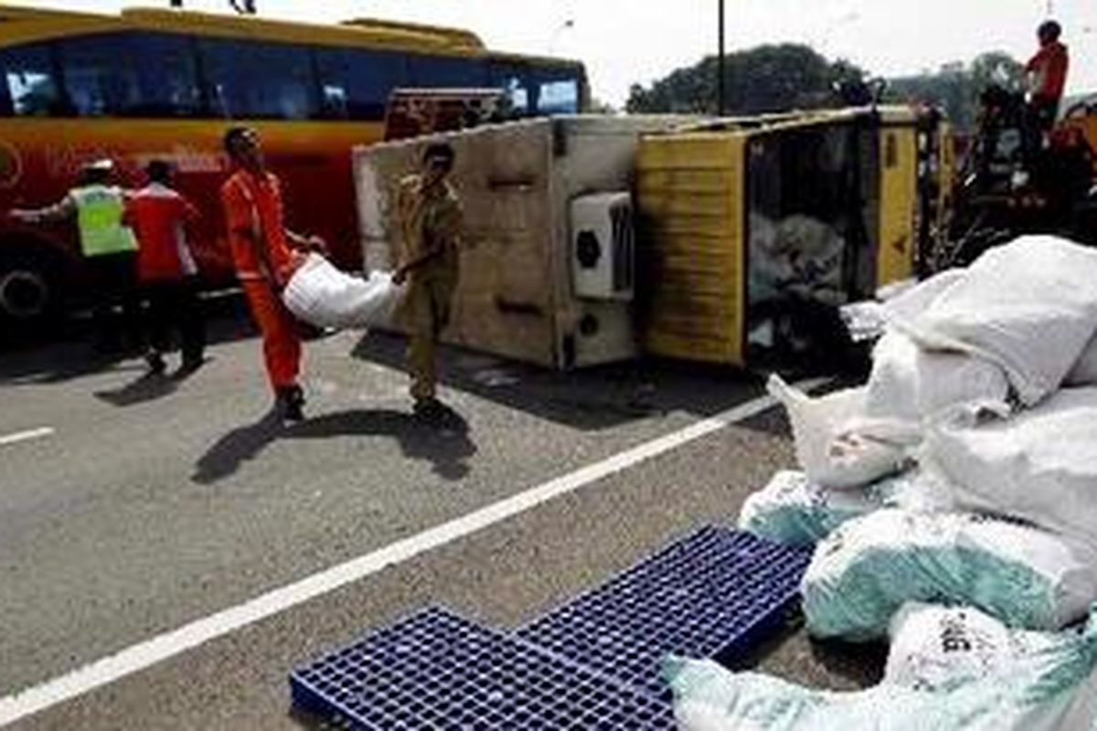 Karyawan KFC memindahkan muatan truk B 9319 SQ yang terguling di jalan tol dalam kota, Jalan Gatot Subroto KM 9 arah Cawang, Jakarta Pusat, Jumat (24/9/2010). Truk yang bermuatan 2.000 ekor ayam beku ini mengalami pecah ban sekitar pukul 14.10 WIB. Tidak ada korban jiwa dalam peristiwa tersebut, namun menyebabkan kemacetan hingga lima kilometer.