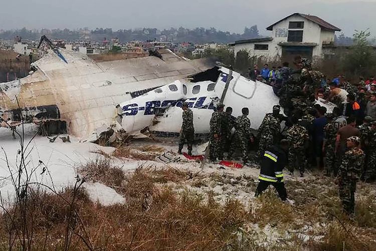 Tim penyelamat dan tentara berada di sekitar pesawat milik maskapai US-Bangla yang mengalami kecelakaan di bandara Tribuvhan, Kathmandu, Nepal, Senin (12/3/2018).