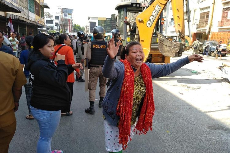 Seorang pedagang meluapkan kemarahannya saat tenda jualannya dirobohkan oleh mesin alat berat yang dibawa Satpol PP dalam penertiban PKL di Jalan Bulan Medan, Kamis (8/8/2019). Jalan Bulan merupakan salah satu pusat grosir bunga krisan di Medan.