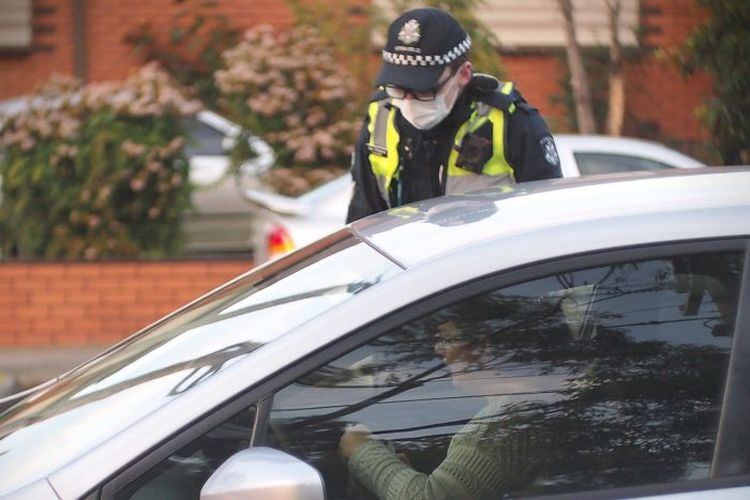 Seorang polisi memeriksa surat-surat peng.endara mobil saat check-point virus corona di Melbourne, Australia, pada Kamis (2/7/2020)