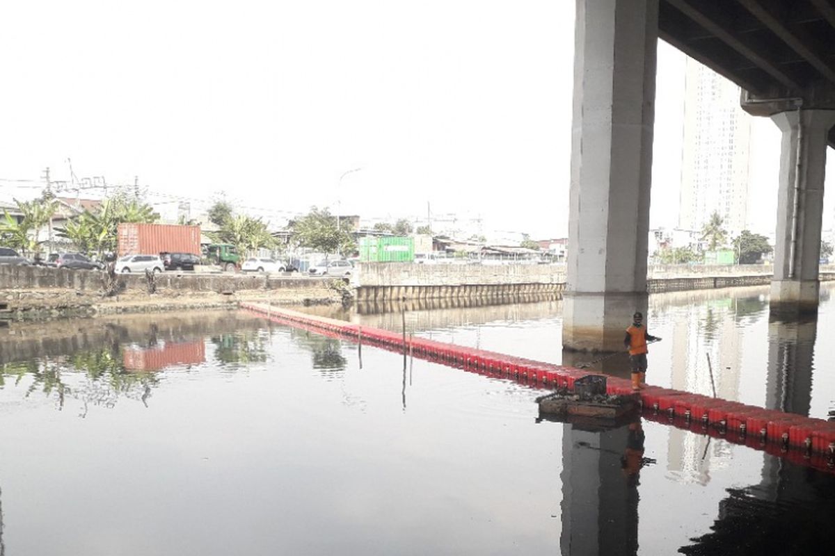 Seorang petugas tengah membersihkan sampah yang mengambang di Kali Ancol, Jakarta Utara, Rabu (25/7/2018).