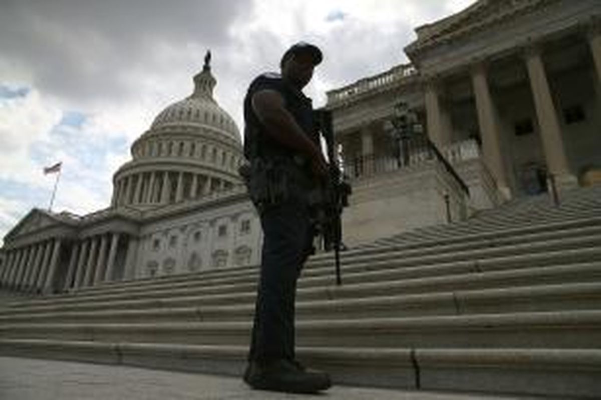 Seorang polisi terlihat bersenjata lengkap mengamankan gedung Capitol di Capitol Hill, Washington, Amerika Serikat, Senin (16/9/2013), menyusul penembakan di pangkalan Angkatan Laut Amerika Serikat yang berjarak kurang dari 3 kilometer dari gedung Senat Amerika ini.