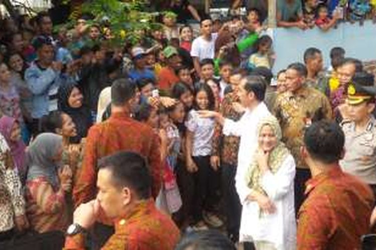 Presiden Jokowi dan Ibu Negara Iriana saat membagi-bagikan paket sembako di Kampung Lio, Pancoran Mas, Depok, Jawa Barat, Jumat (1/7/2016).