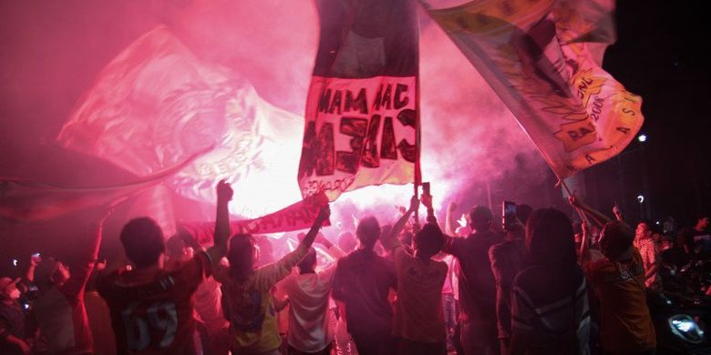 Suporter Persija menyalakan flare saat merayakan kemenangan Persija Jakarta pada laga final Piala Menpora 2021 di Bundaran Hotel Indonesia, Jakarta, Senin (26/4/2021). Suporter Persija The Jakmania berkonvoi memadati Bundaran HI merayakan kemenangan Persija Jakarta menjadi juara Piala Menpora 2021 usai mengalahkan Persib Bandung di Stadion Manahan Solo dengan agregrat 4-1. . 