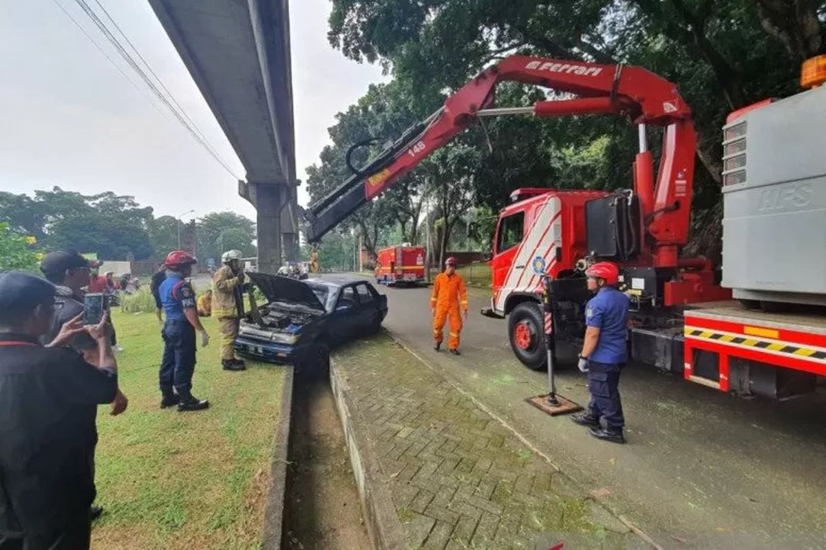 Petugas Damkar Jakarta Timur mengerahkan satu alat berat untuk memindahkan mobil dan pengendaranya yang terperosok di saluran air TMII, Jakarta Timur, Minggu (8/3/2020).