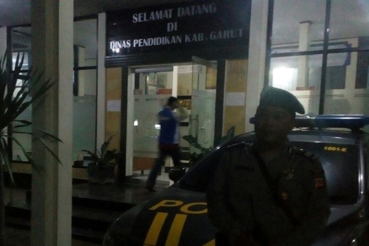 Seorang anggota Kepolisian dari Polsek Cibatu yang datang ke Kantor Dinas pendidikan Garut untuk mengambil soal harus menunggu soal yang terlambat datang.