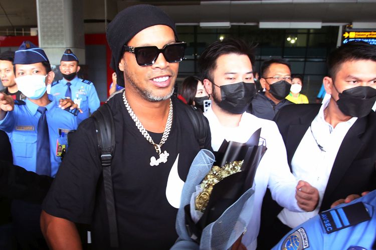 Mantan pesepak bola dunia asal Brasil Ronaldinho (tengah) berjalan keluar terminal setibanya di Bandara Soekarno Hatta, Tangerang, Banten, Jumat (24/6/2022). Legenda sepak bola Brasil ini nantinya akan memperkuat RANS Nusantara FC pada laga trofeo menghadapi Arema FC dan Persik Kediri, Minggu (26/6).