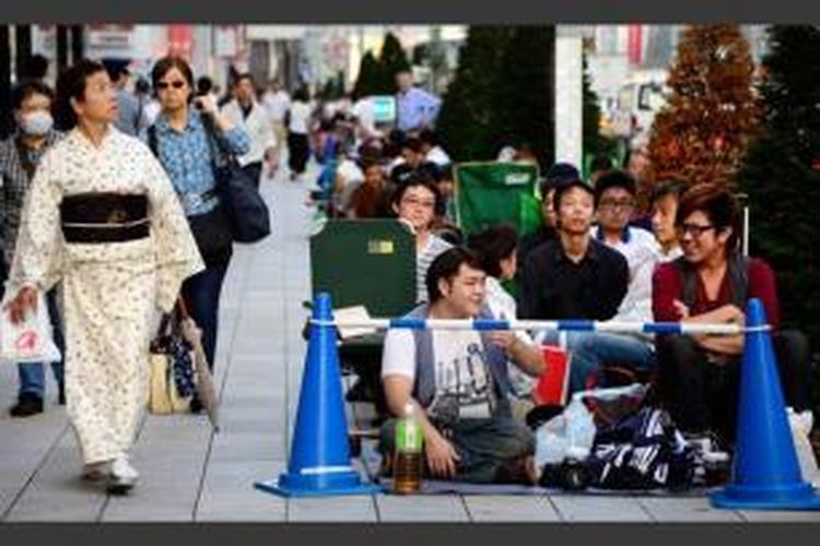 Seorang wanita berkimono berjalan di samping antrean warga di depan Apple Store di Ginza, Tokyo untuk membeli iPhone terbaru, 19 September 2013. Apple resmi memasarkan produk terbaru iPhone 5s dan 5c ke seluruh dunia.