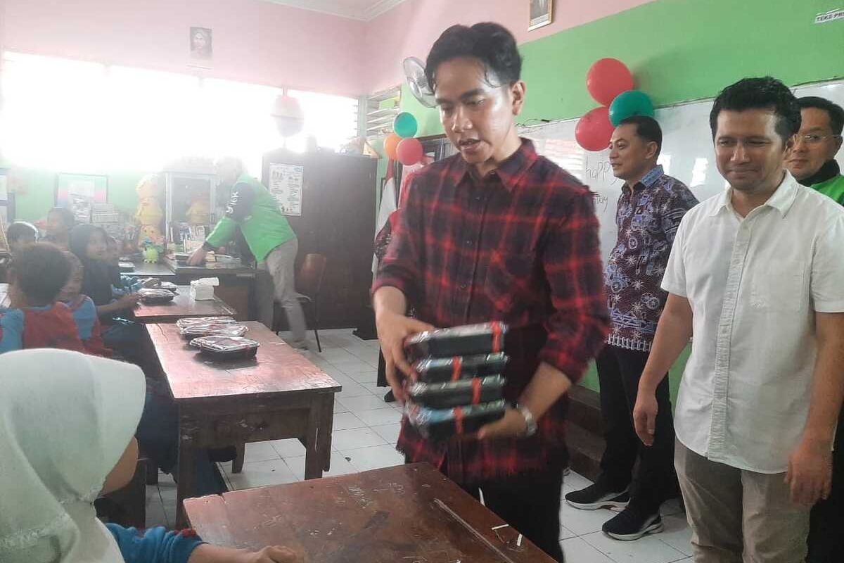 Wapres terpilih Gibran Rakabuming Raka membagikan makanan bergizi gratis di SDN Klampis III Surabaya, Kamis (1/8/2024).