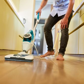 Ilustrasi membersihkan lantai dengan steam mop atau pel uap.