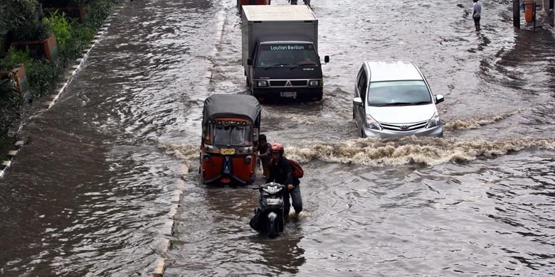 Sejumlah kendaraan melintasi banjir yang menggenangi Jalan Gunung Sahari Raya, Pademangan, Jakarta Utara, Jumat (17/1/2014). Hujan lebat yang mengguyur Jakarta sejak pagi, membuat jalan tersebut tergenang dan diperparah sistem drainase yang kurang baik. 