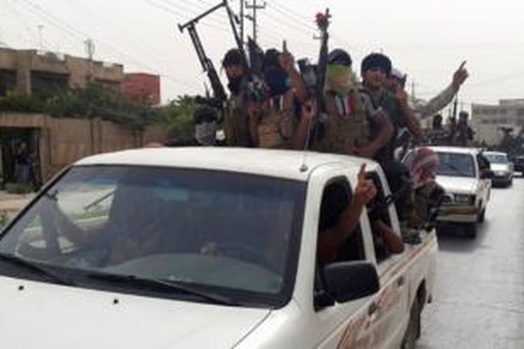 Para pejuang ISIS berkonvoi di jalanan kota Mosul menggunakan mobil-mobil yang mereka rampas dari pasukan Irak.