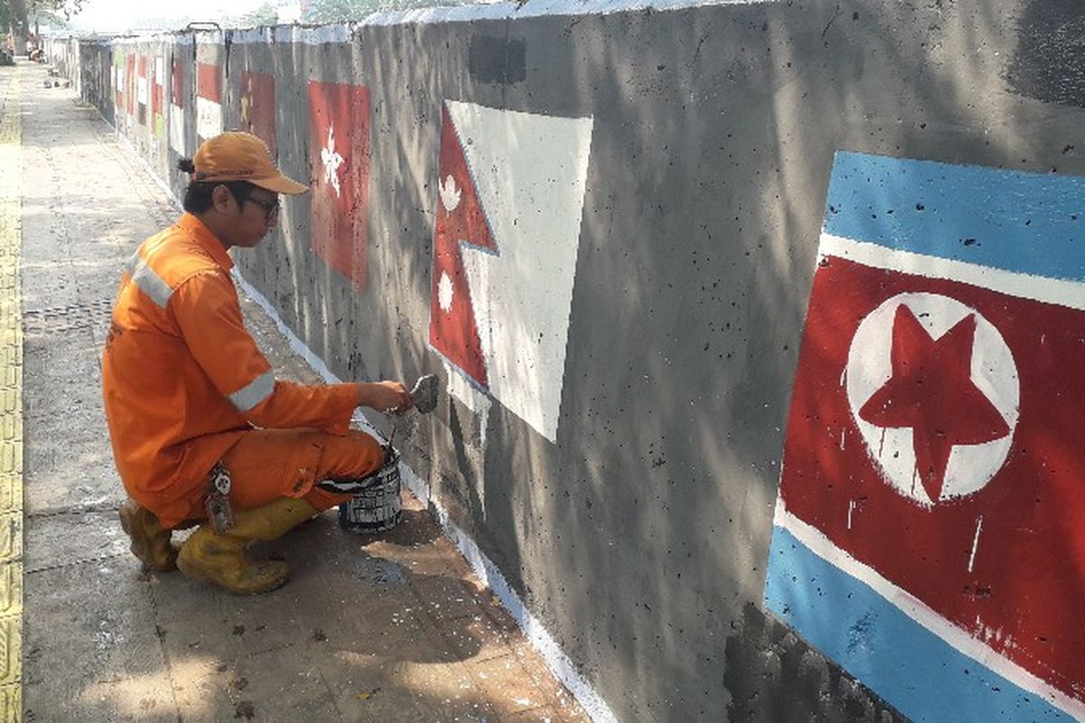 Petugas Penanganan Prasarana dan Sarana Umum (PPSU) Rawa Buaya membuat mural di tembok jalan pembatas Kali Mookervart, Jakarta Barat pada Senin (30/7/2018).