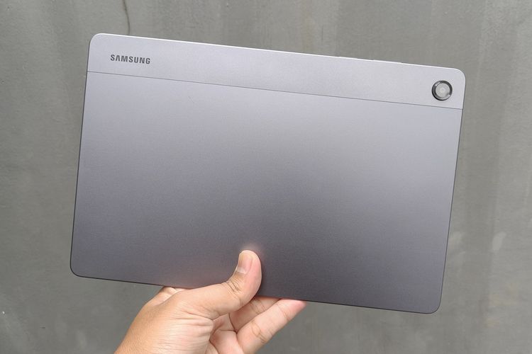 Bagian belakang tablet Samsung Galaxy Tab A11 Plus yang berwarna abu-abu. Di sini juga ada tulisan Samsung dengan satu modul kamera.
