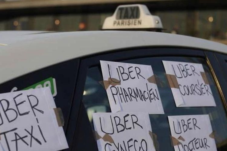 Taksi dengan tulisan Uber Taksi, Uber Apoteker, Uber dokter diparkir di luar Terminal Barat Bandara Orly di Orly, Paris selatan, 25 Juni 2015. Ratusan sopir taksi berunjuk rasa di Paris menentang keberadaan aplikasi layanan sewa mobil Uber.