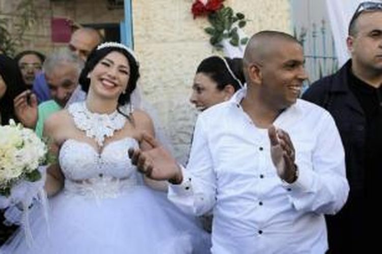 Pasangan pengantin Maral Malka dan Mahmoud Mansour tetap bergembira merayakan pernikahan mereka di pinggiran kota Tel Aviv meski menghadapi aksi protes kelompok ekstrem kanan Yahudi.